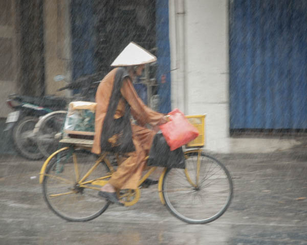 Frau auf einem Fahrrad im Regen in Hue